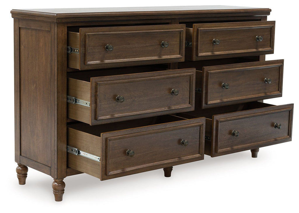 Brown dresser showing six drawers, long pulls, and carved trim with turned legs