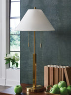 Gold floor lamp with white shade, round base, and hanging pull cords.