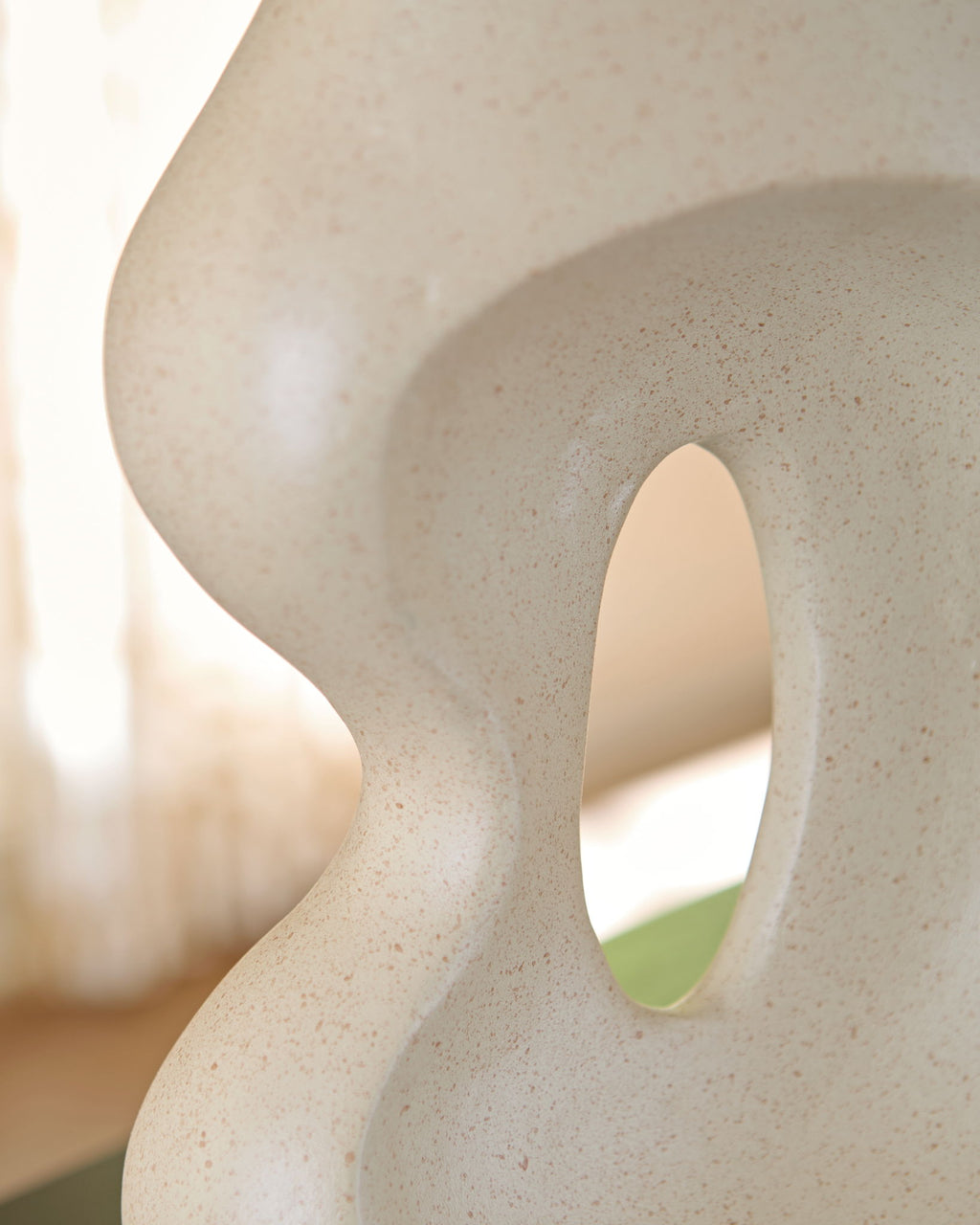 Beige ceramic vase close-up of side cutout and rounded neck opening.