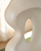 Beige ceramic vase close-up of side cutout and rounded neck opening.
