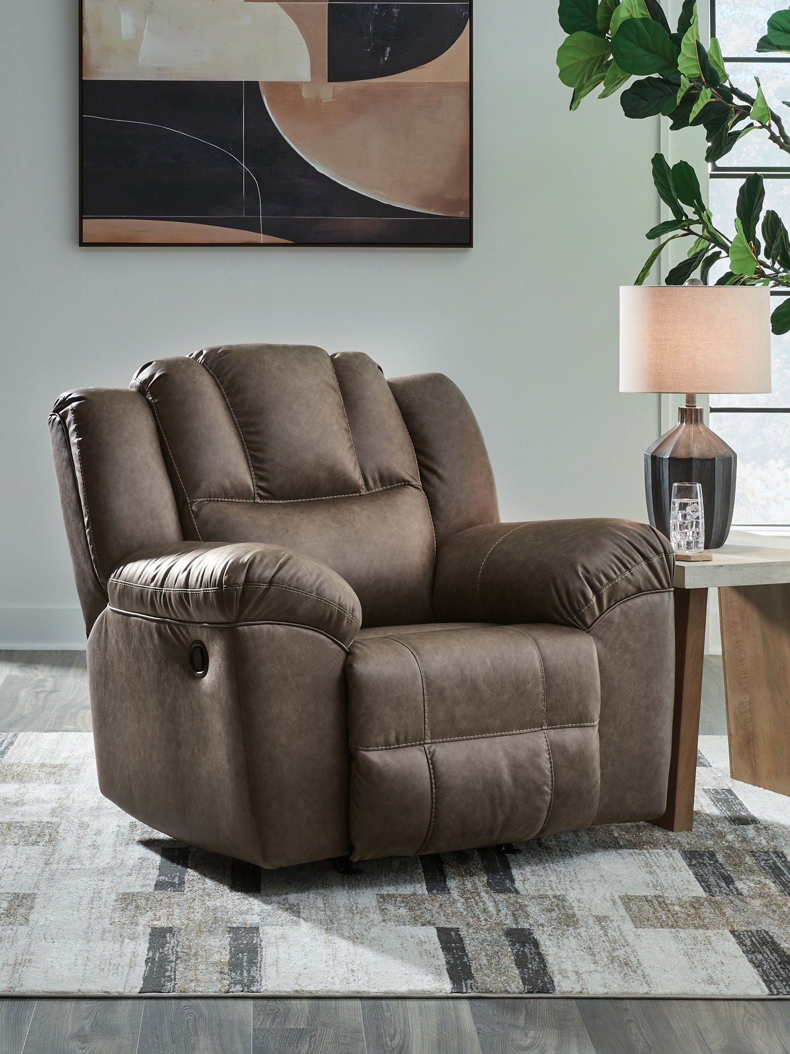 Brown rocker recliner chair with padded arms, tufted back, and recline footrest