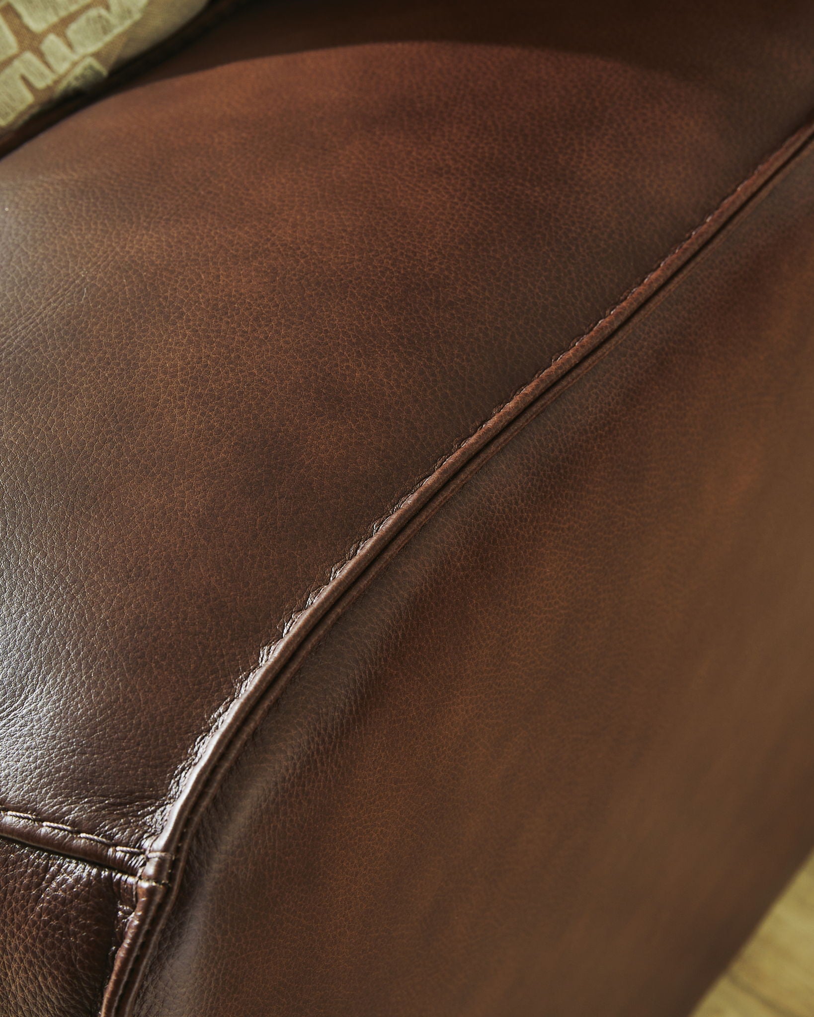 Dark brown faux leather upholstery detail with stitched seams and curved panel edge