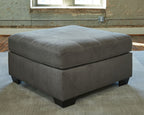 Gray square ottoman with padded seat, subtle tufting, and block feet