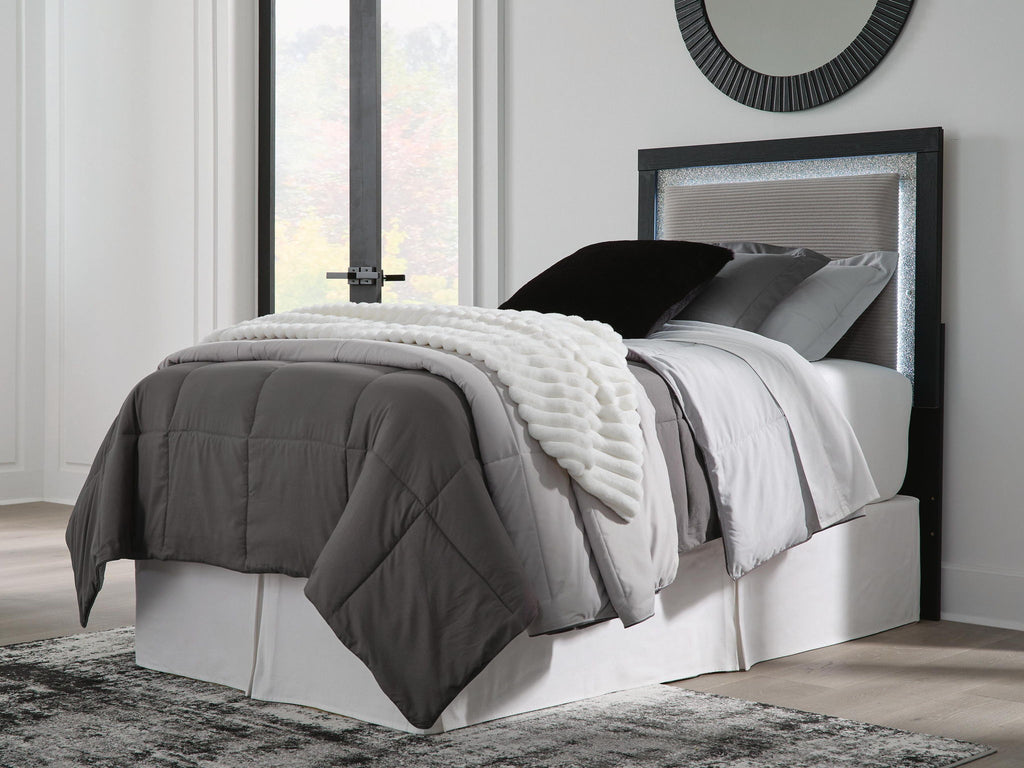 Light gray upholstered panel headboard with dark frame, holding pillows and bedding.