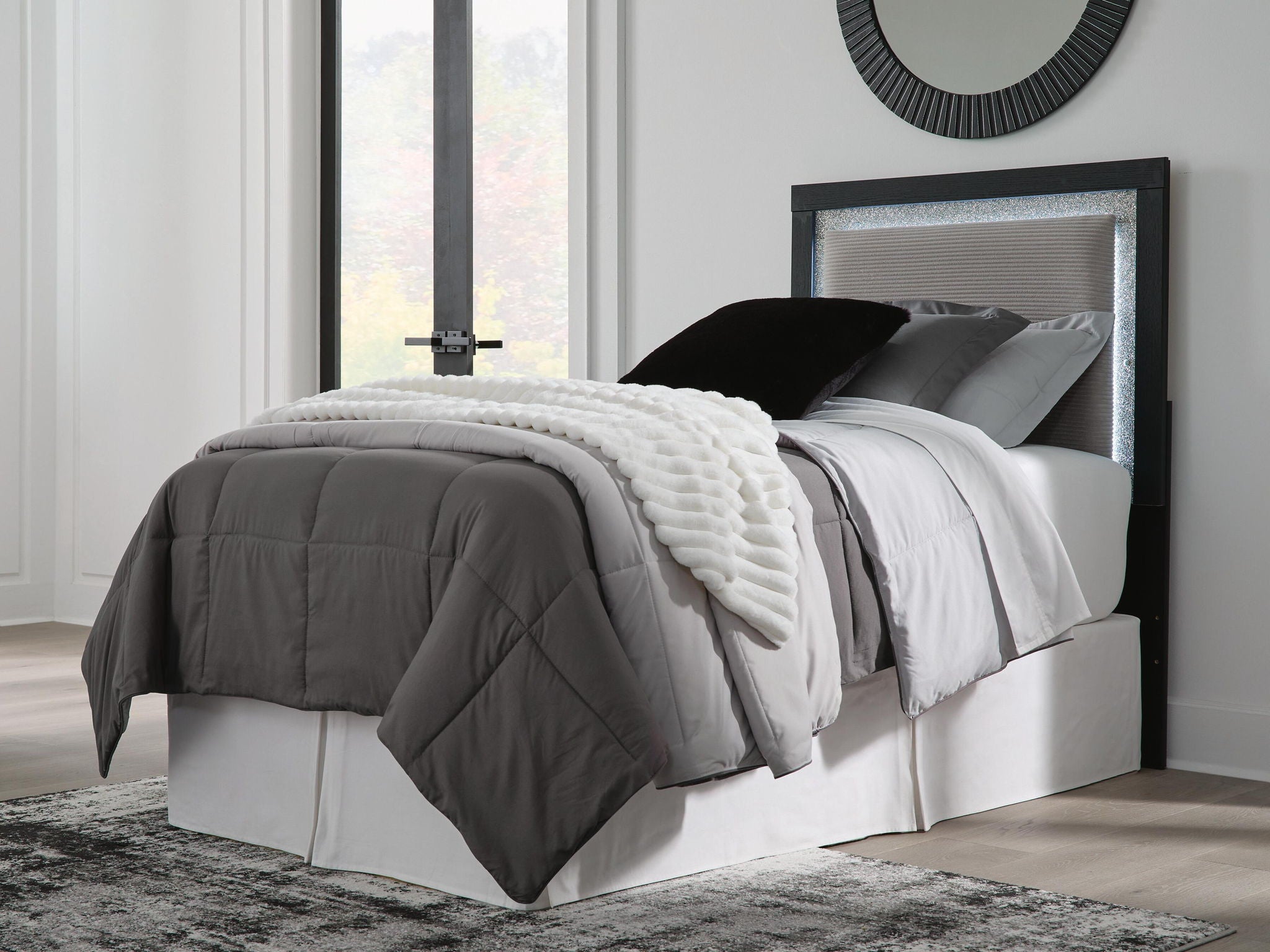 Light gray upholstered panel headboard with dark frame, holding pillows and bedding.