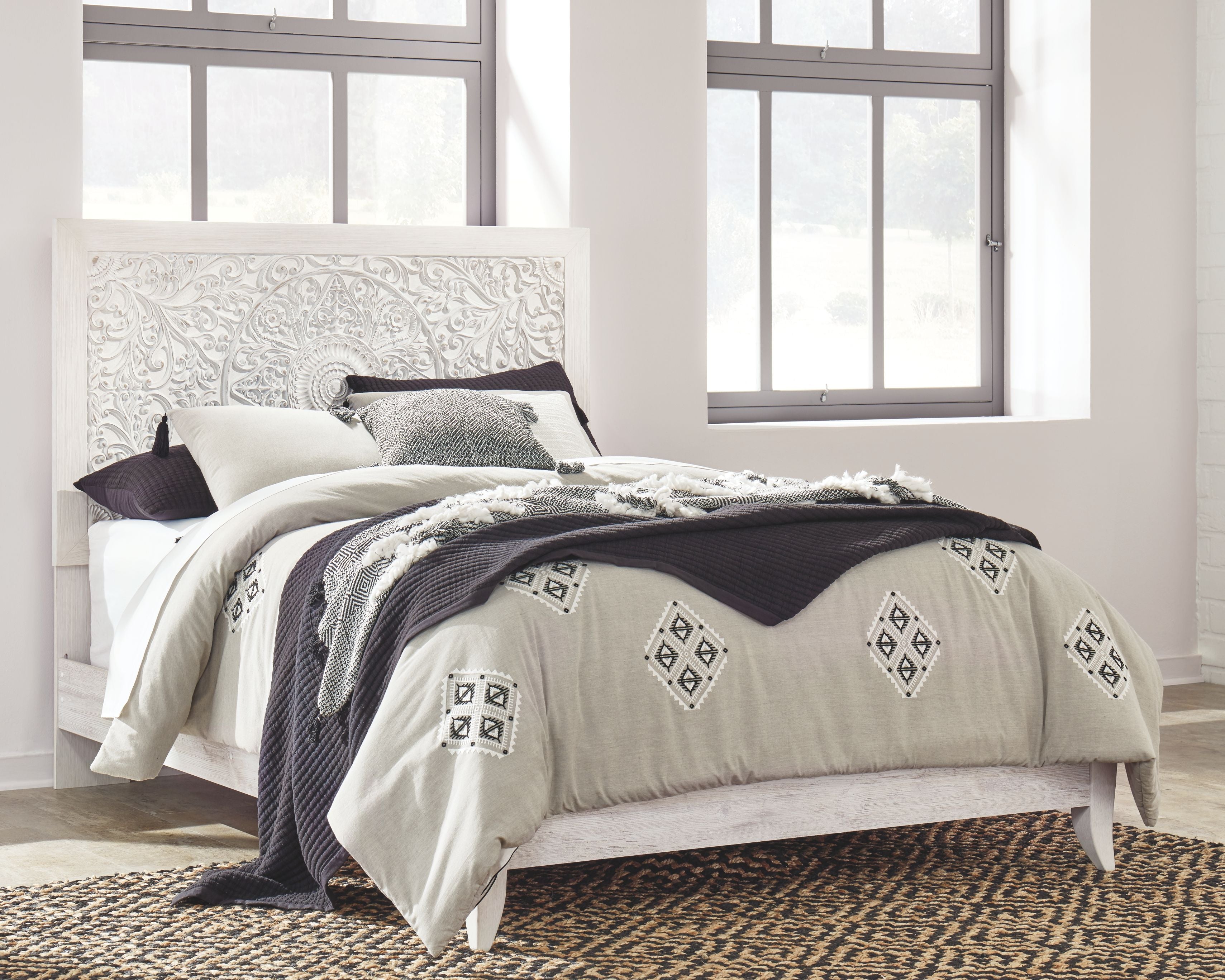 Whitewash queen panel headboard with upholstered white bed and patterned bedding
