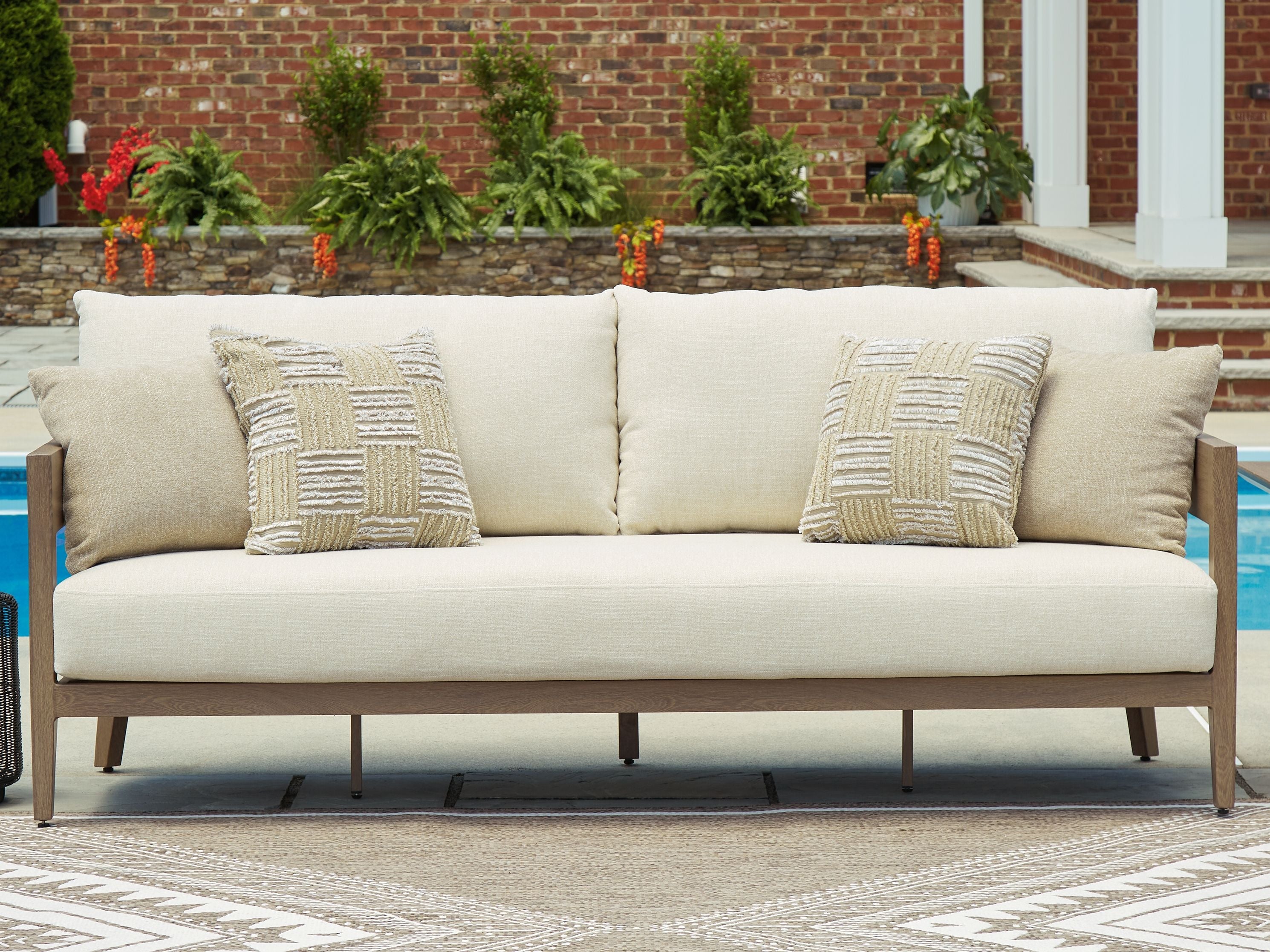 Beige sofa with two patterned beige cushions and dark brown wooden legs