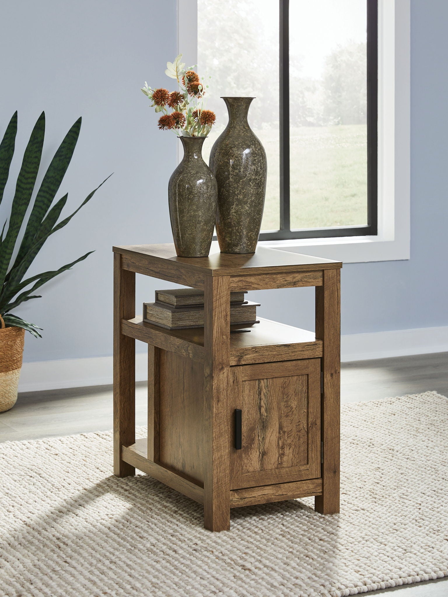 Chair side end table with open shelf and one-door cabinet, warm light brown wood, black handle.