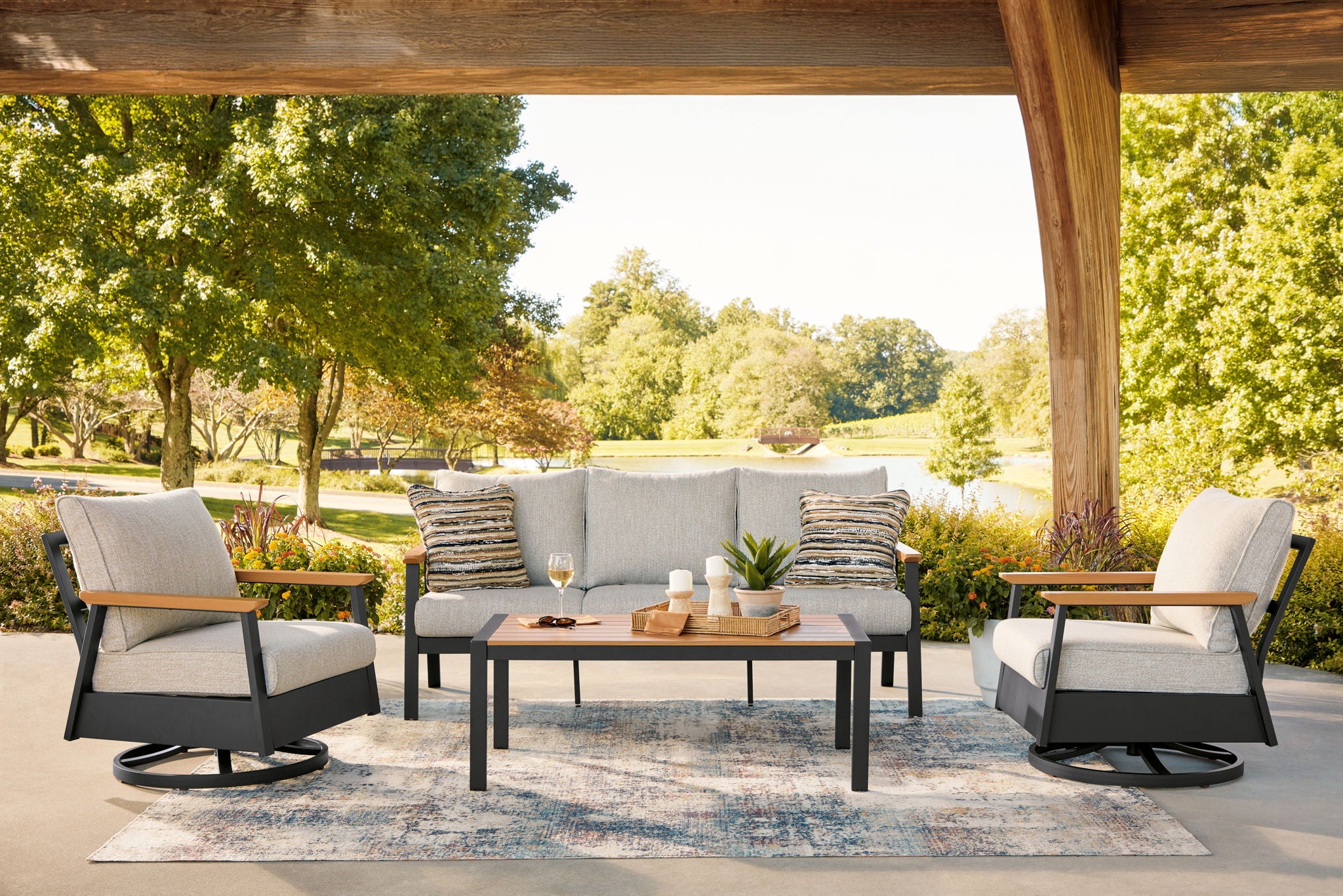 Outdoor sofa and two swivel chairs set with gray cushions and dark coffee table