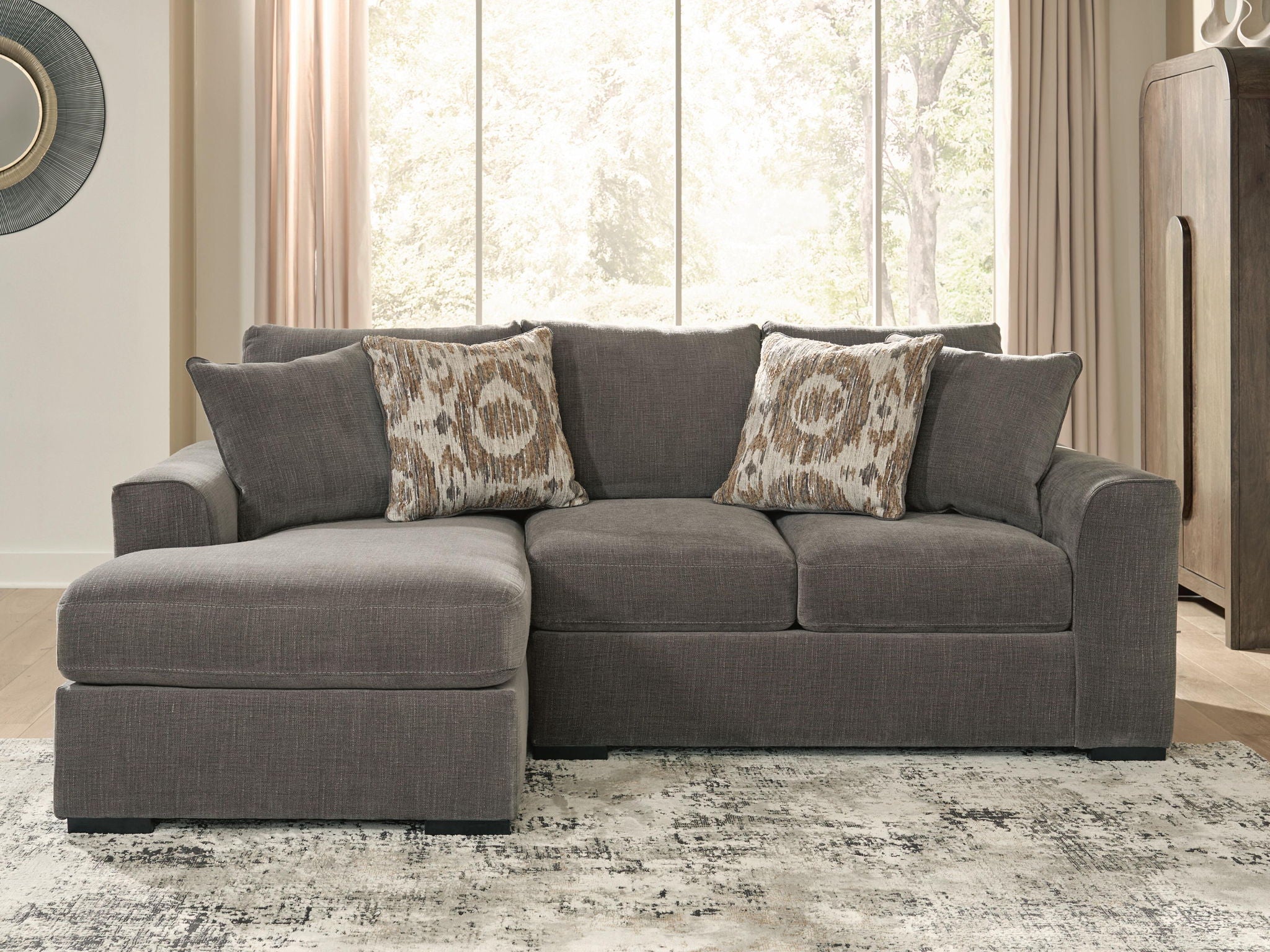 Gray sectional sofa with chaise cushion and two patterned throw pillows