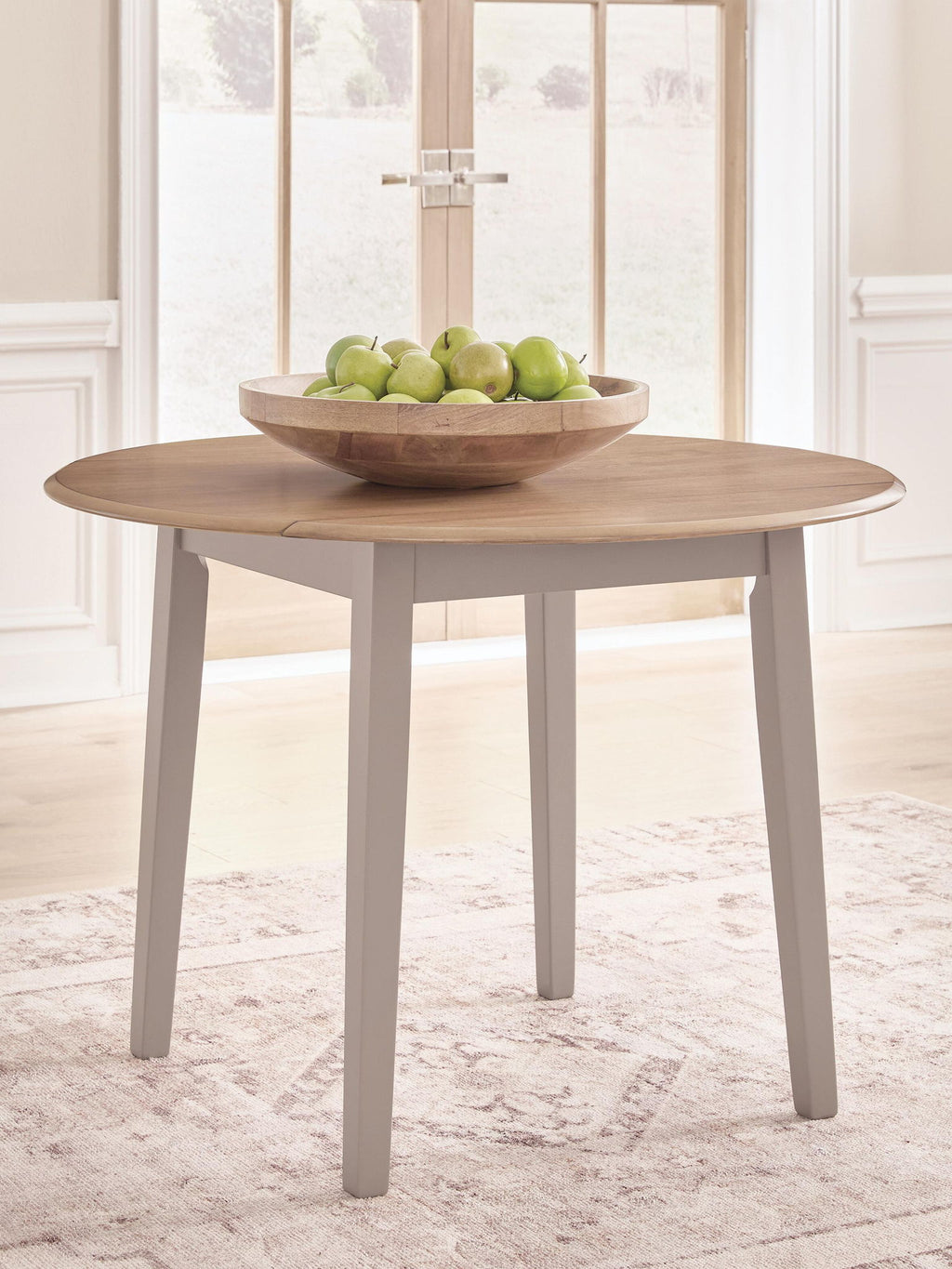 Round drop-leaf dining table with natural wood top and gray legs, leaves up