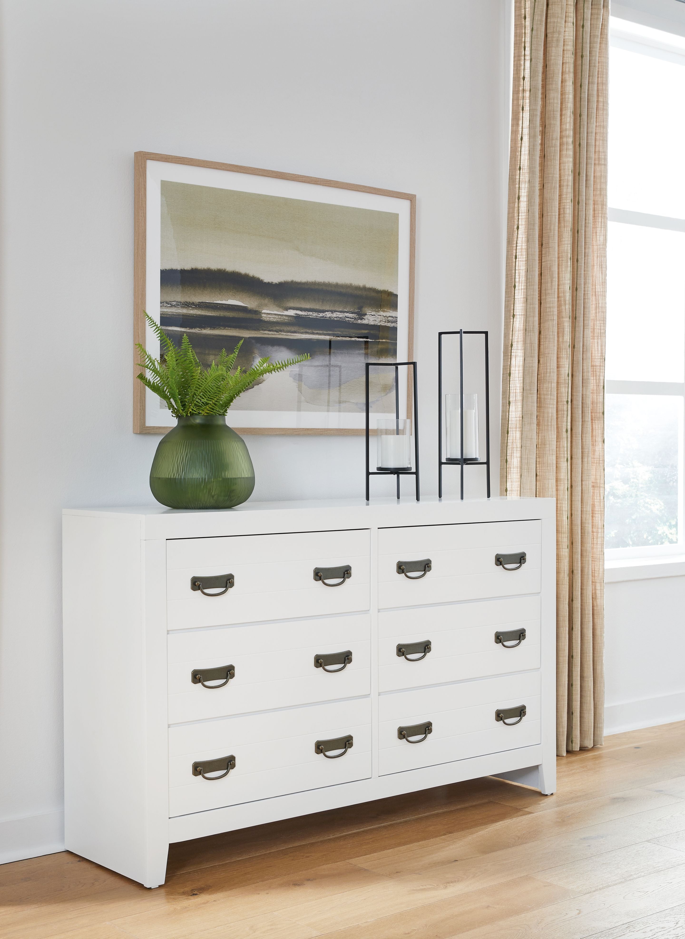 White dresser with 9 drawers and dark pull handles, front view