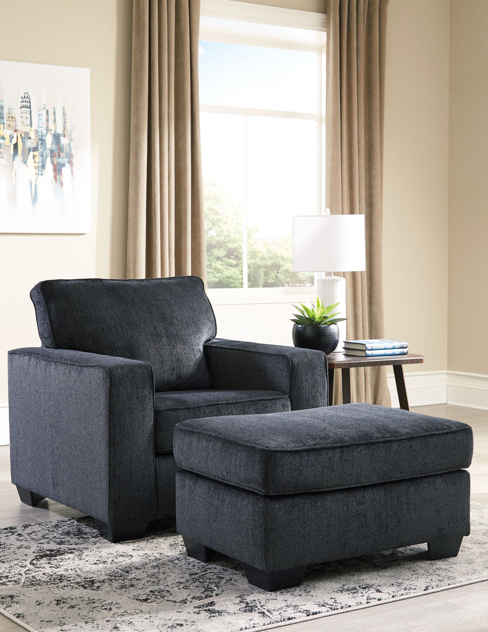 Dark gray upholstered ottoman with cushioned top and block legs