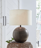 Metal table lamp with beige shade and dark speckled globe base on woven stand