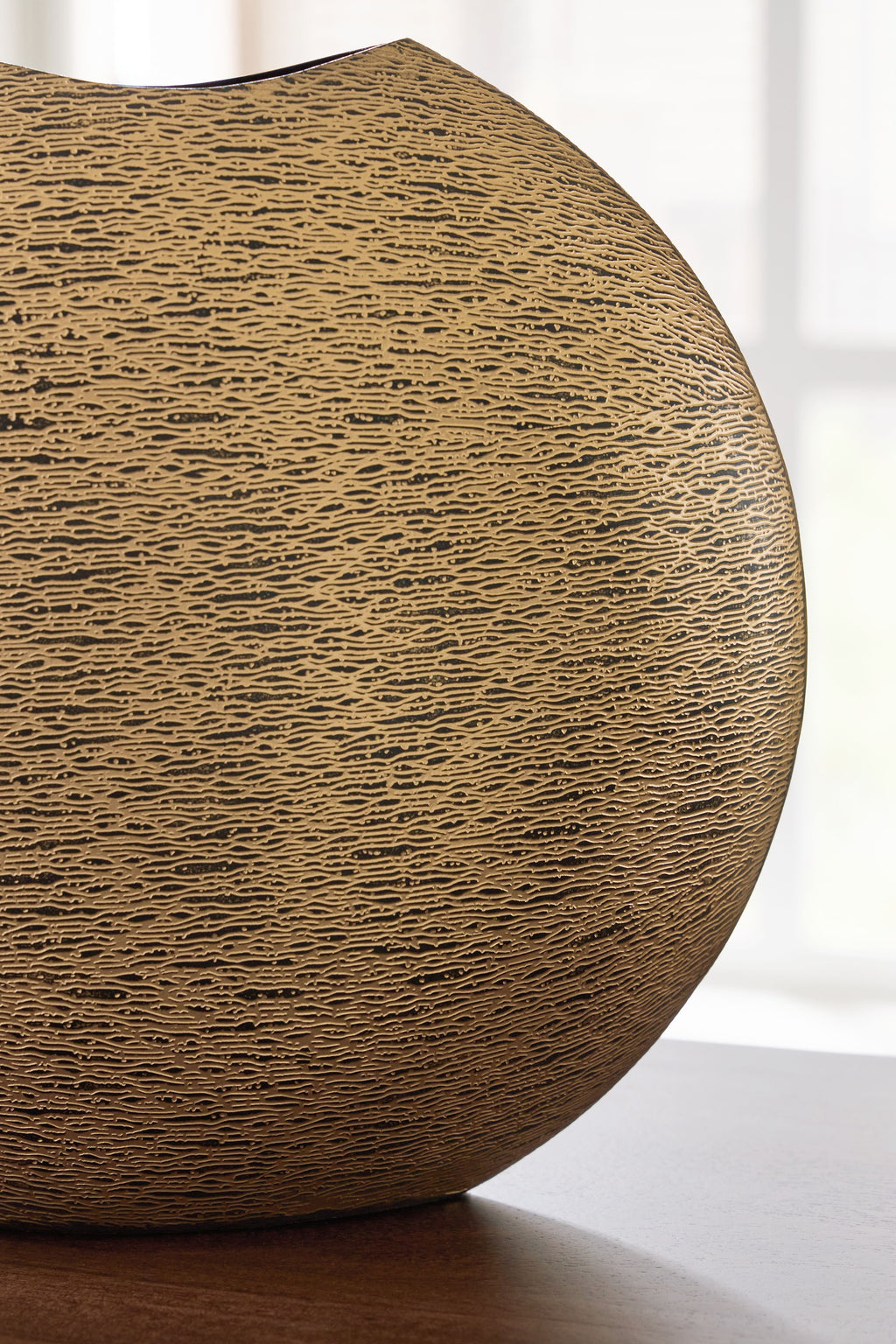 Gold textured vase shown from side, with dark top opening