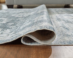 Rolled section of gray washable rug showing underside and distressed floral print