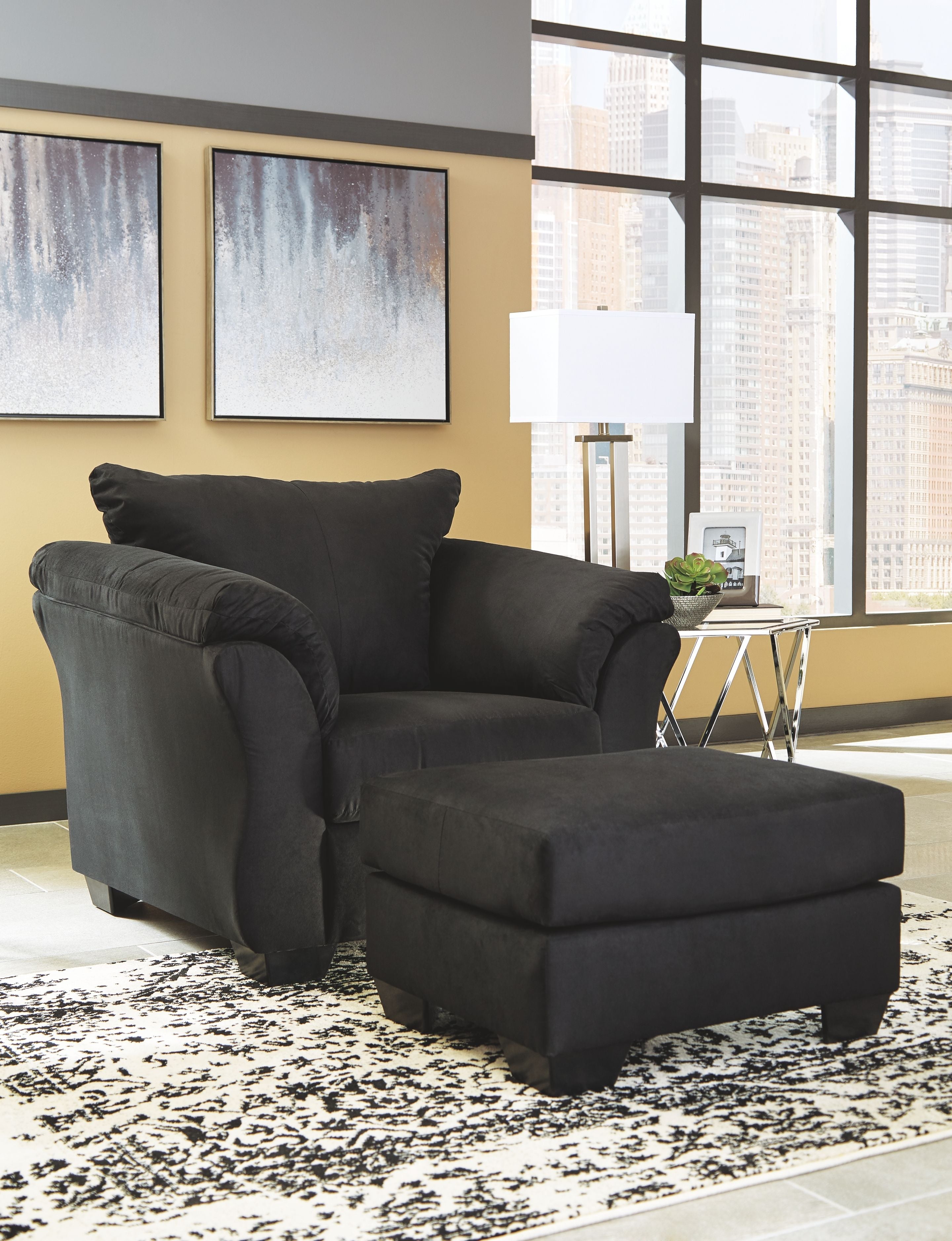 Black upholstered armchair with matching ottoman, low back and wide cushioned arms