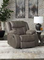 Gunmetal gray fabric rocker recliner with padded arms, rounded back, and footrest