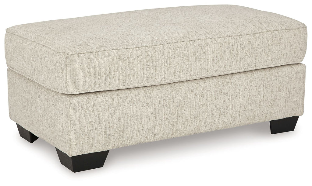 Light beige fabric upholstered ottoman with hinged top and dark legs