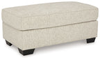 Light beige fabric upholstered ottoman with hinged top and dark legs