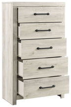 Angled side view: whitewash chest of drawers, five open drawers, black bar handles