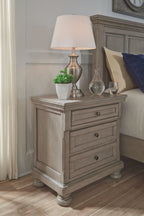 Lettner night stand with three drawers and lamp on top, light gray finish.