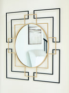 Round accent mirror with gold edge and black geometric frame, showing reflected room.