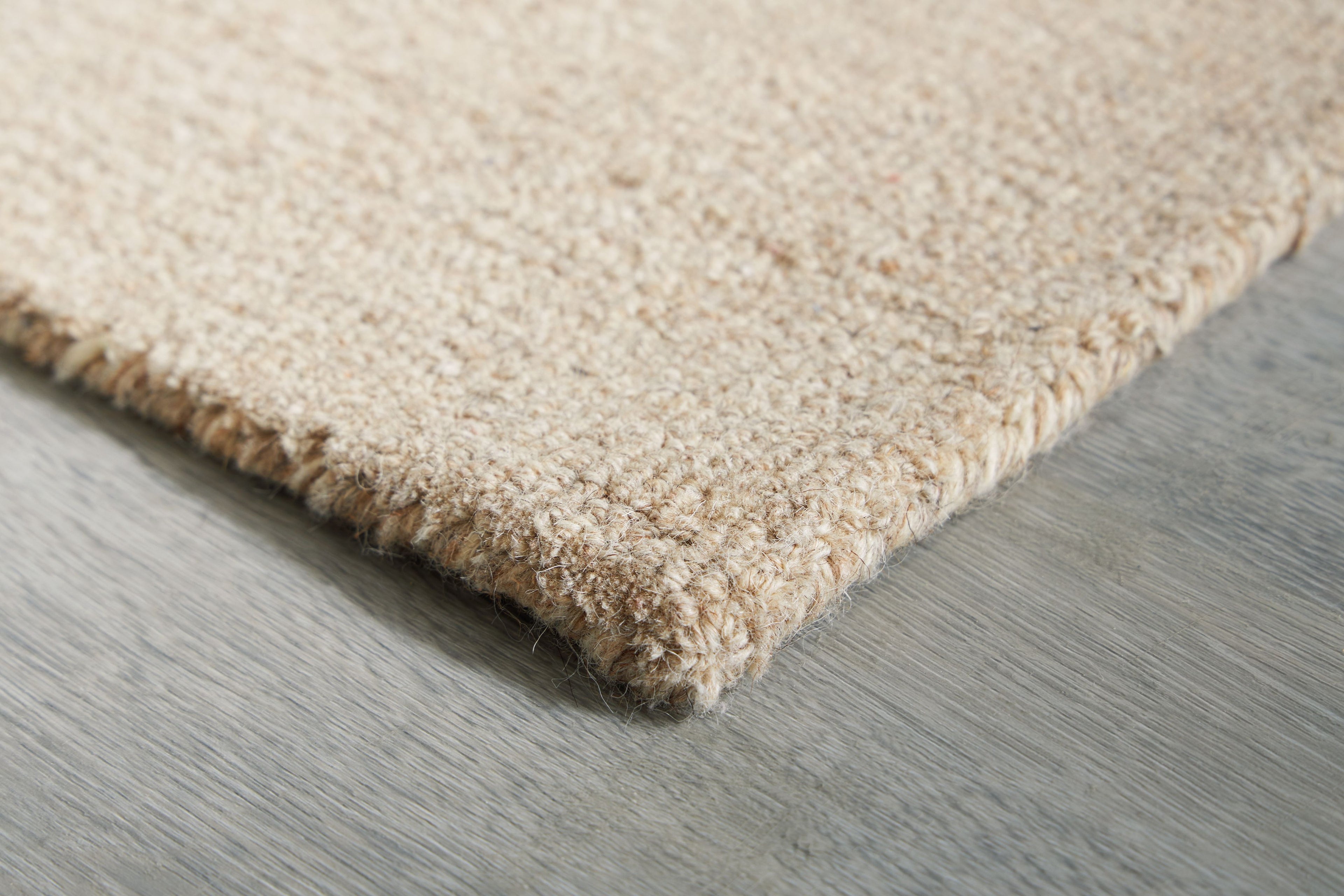 Area rug corner close-up with short shag-like texture and stitched trim edge
