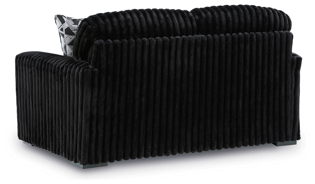 Black corduroy loveseat with tufted back and one patterned side pillow