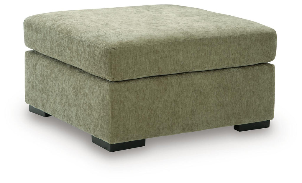 Oversized accent ottoman in green upholstered fabric with thick padded lid and dark block legs.
