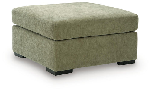 Oversized accent ottoman in green upholstered fabric with thick padded lid and dark block legs.