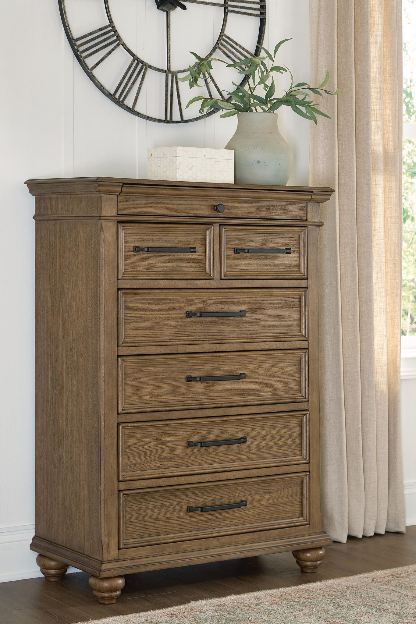 Medium brown wooden chest of drawers with seven drawers and dark bar pulls