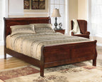 Dark brown sleigh bed with paneled headboard and footboard, patterned bedding