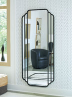 Black arched floor mirror with scalloped frame, standing against wall