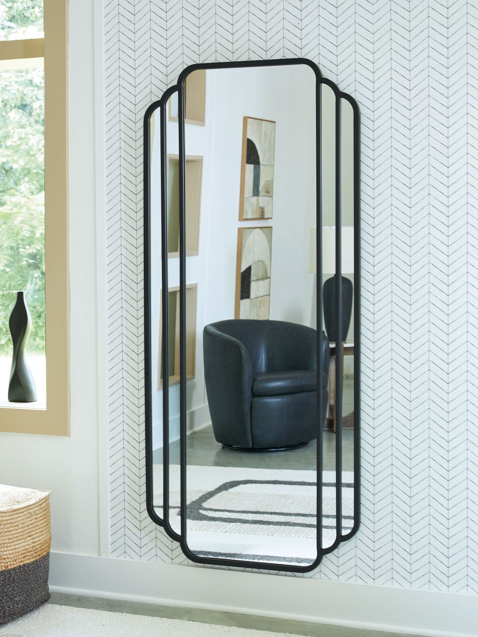 Black arched floor mirror with scalloped frame, standing against wall