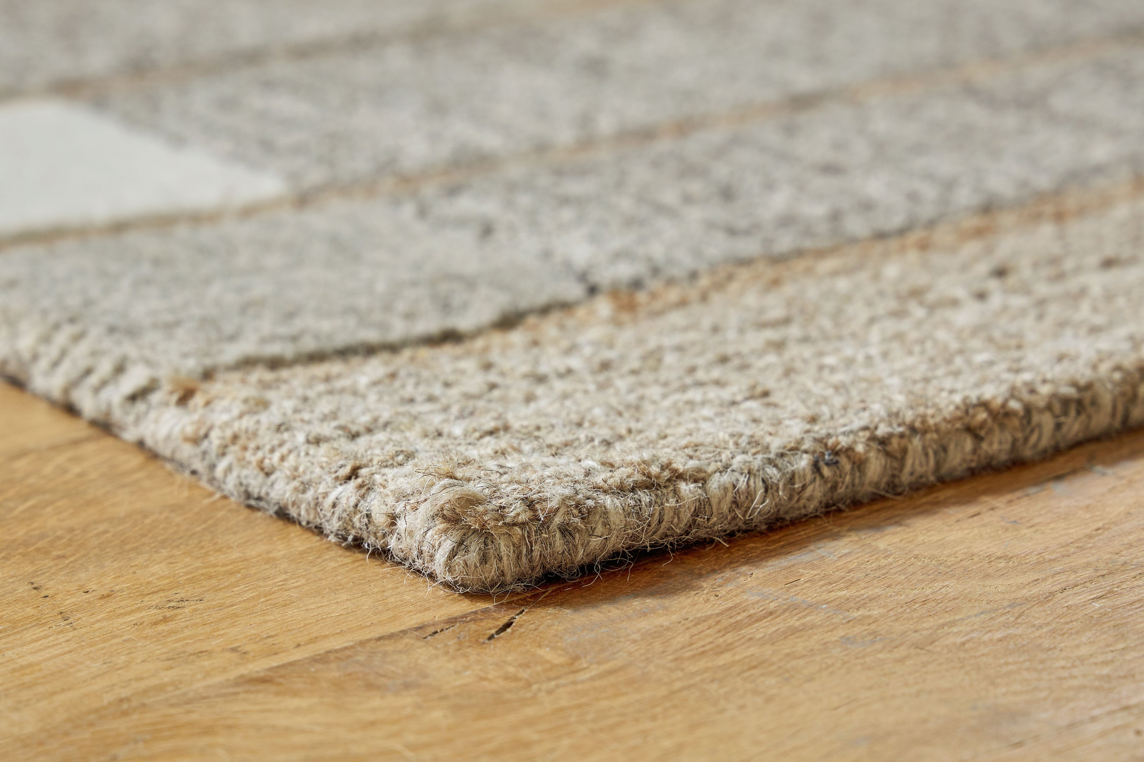 Abbotton rug corner detail with fringed, textured surface in light tones