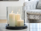 Glass cylinder candle holder with dark base, holding four lit white candles