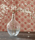 Clear speckled glass vase with dried floral stems, narrow neck and bulb shape.