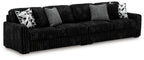 Charcoal sectional sofa with deep seat and multiple geometric-pattern throw pillows.
