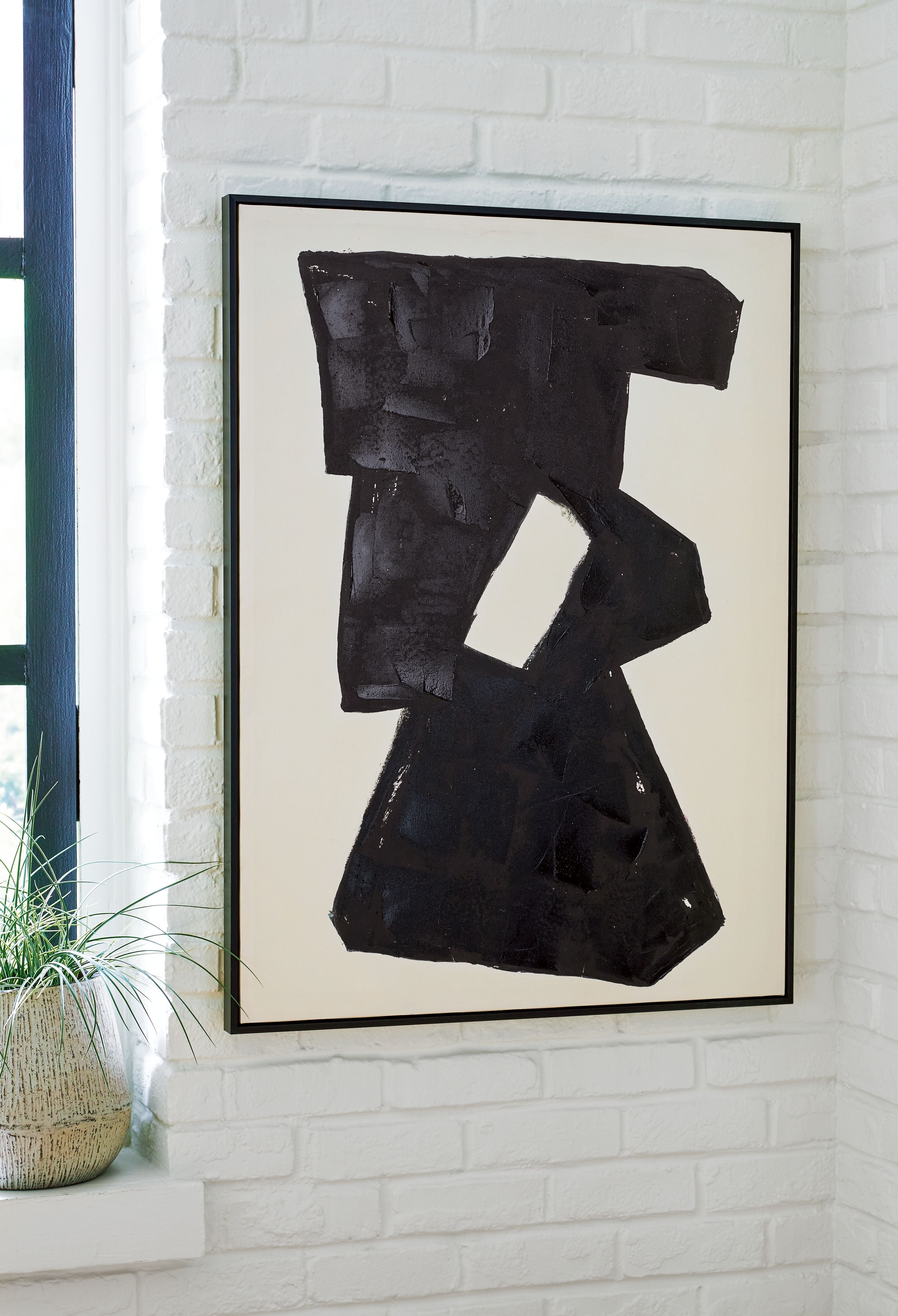 Framed abstract wall art with dark black geometric forms and a hollow cutout