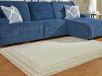 Beige area rug with centered framed pattern and layered border lines