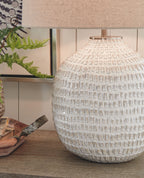 Beige ceramic table lamp with textured globe base and beige fabric drum shade, close-up