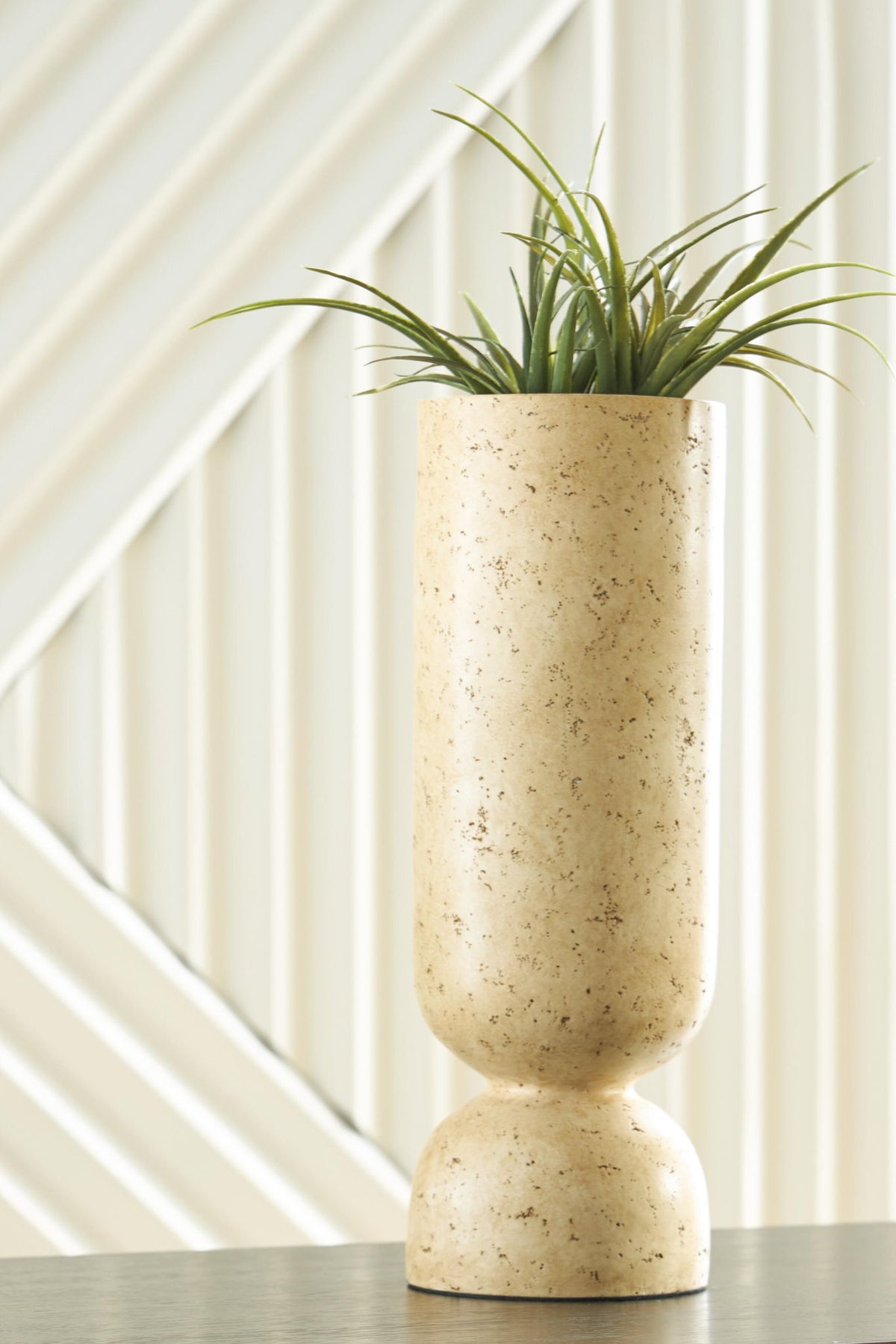 Beige speckled vase with green grass stems, tall fluted silhouette
