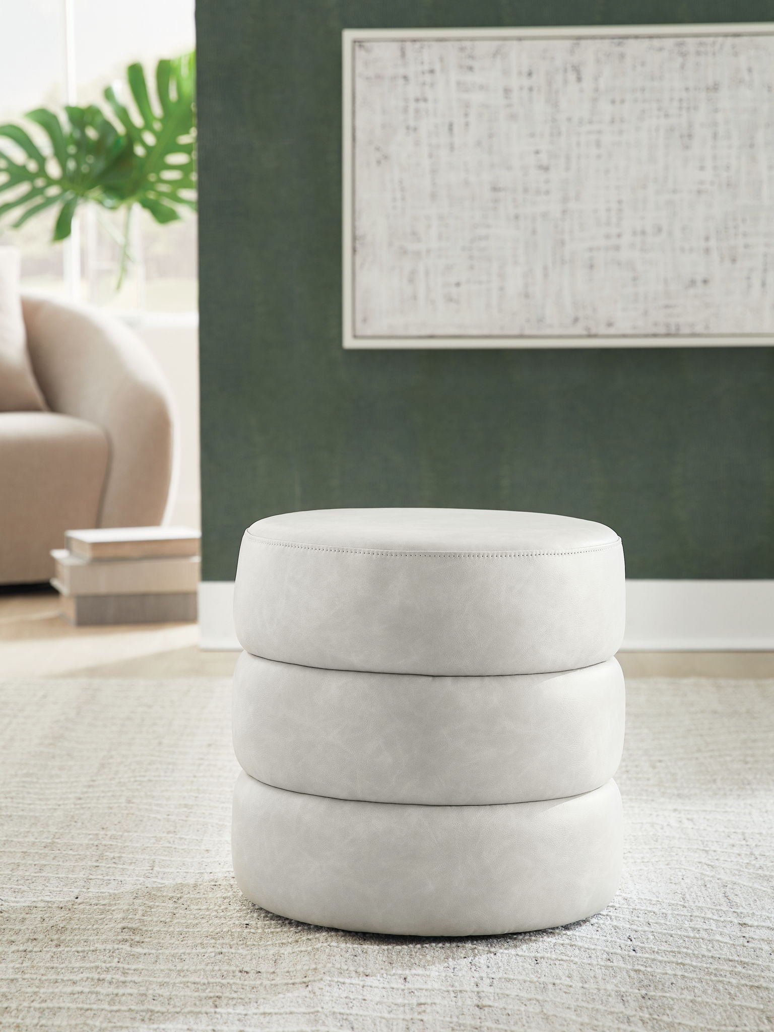 White swivel accent ottoman with round padded top and stacked cylindrical base.
