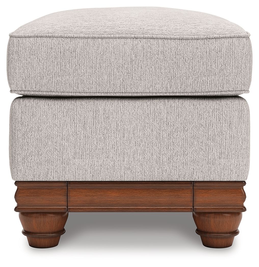 Sandstone upholstered ottoman with padded top and visible wooden legs