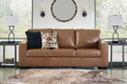 Caramel brown leather sofa with two throw pillows and three padded seat sections