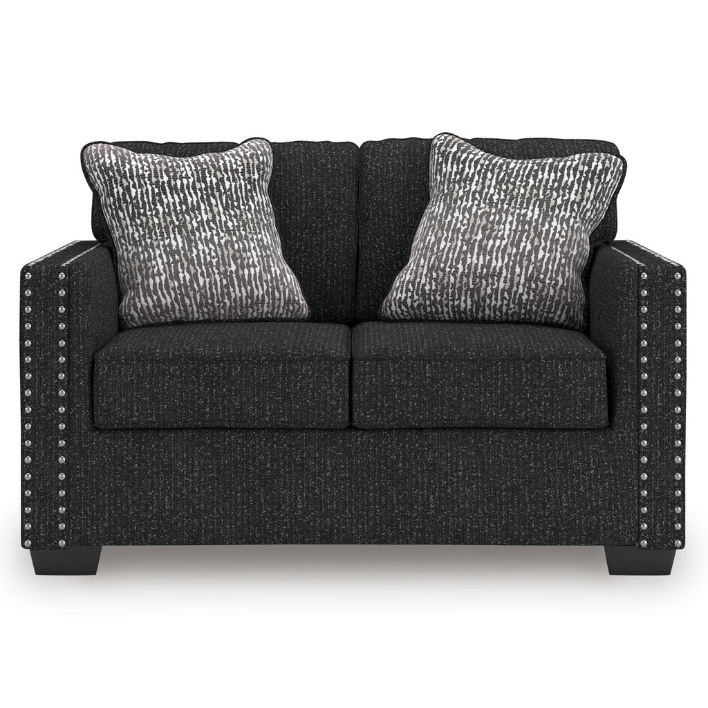 Charcoal loveseat with two patterned throw pillows and studded nailhead side accents