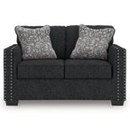 Charcoal loveseat with two patterned throw pillows and studded nailhead side accents