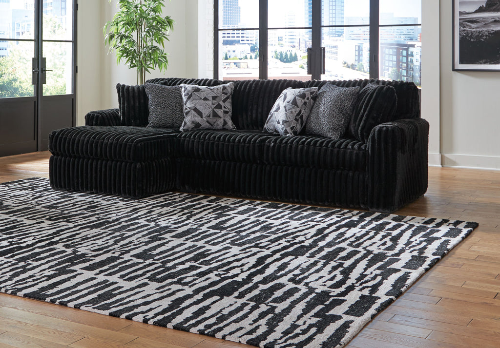 Black corduroy sectional sofa with chaise corner and gray patterned pillows