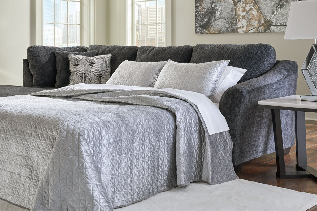 Dark gray sofa sleeper with open bed area and patterned throw pillows